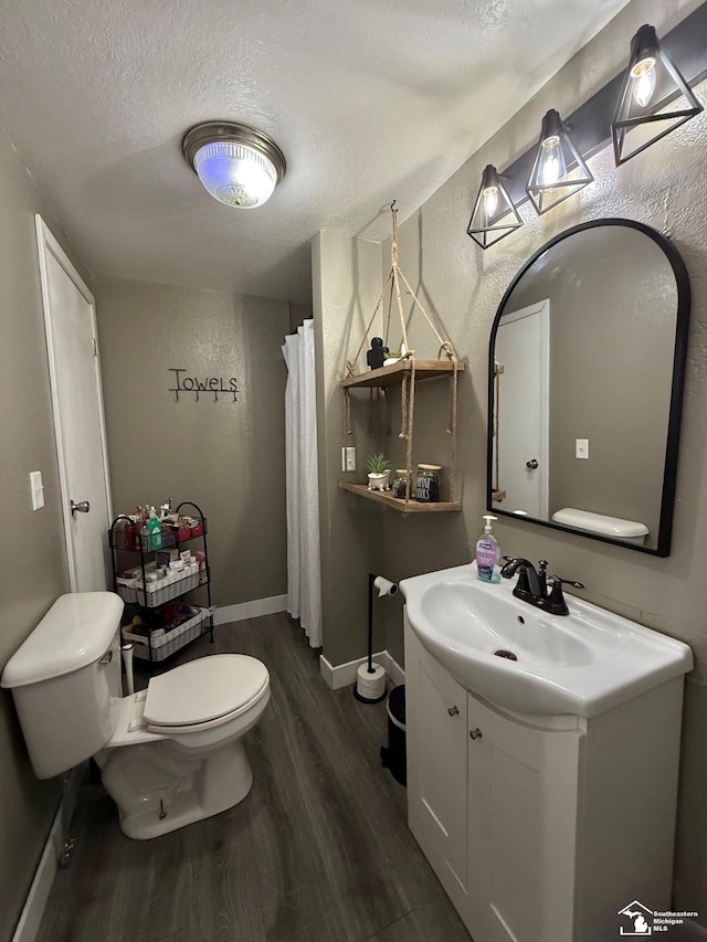 bathroom featuring vanity, a textured ceiling, toilet, and wood finished floors