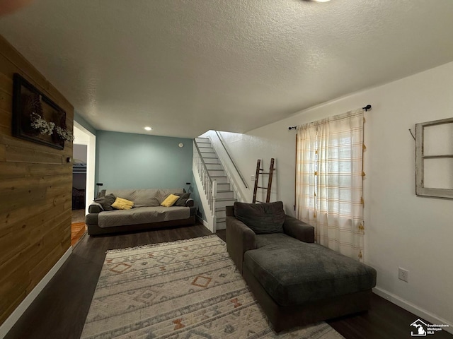 living area with baseboards, a textured ceiling, stairway, and wood finished floors