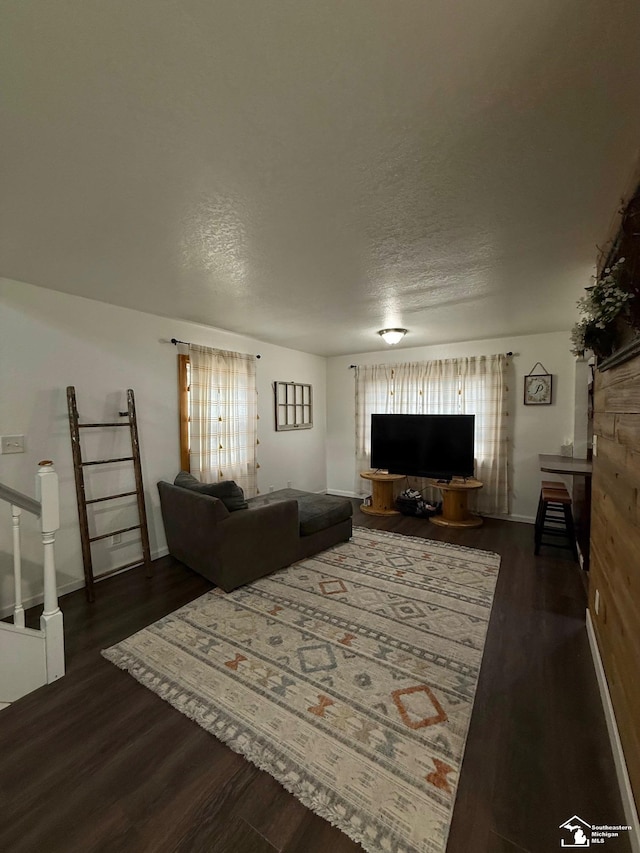 living area with a healthy amount of sunlight, a textured ceiling, stairway, and wood finished floors