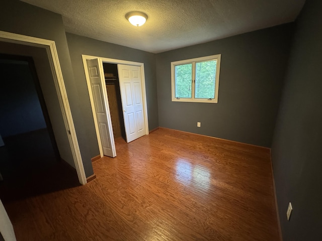 19084 200th Ave, Tustin, MI 49688 - unfurnished bedroom with wood finished floors, a textured ceiling, and a closet