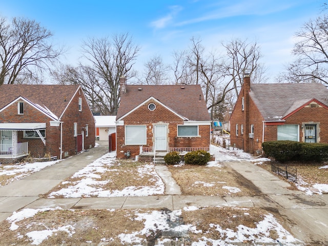 bungalow featuring driveway, brick siding, and a chimney