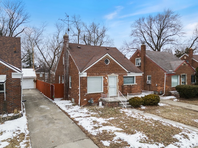 bungalow-style home with an outbuilding, brick siding, and a chimney