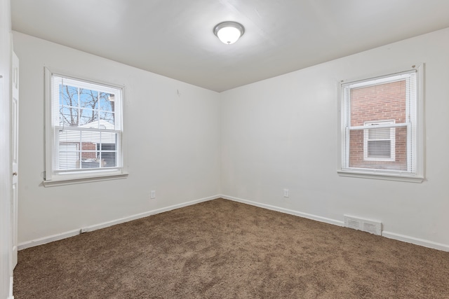 carpeted spare room featuring visible vents and baseboards