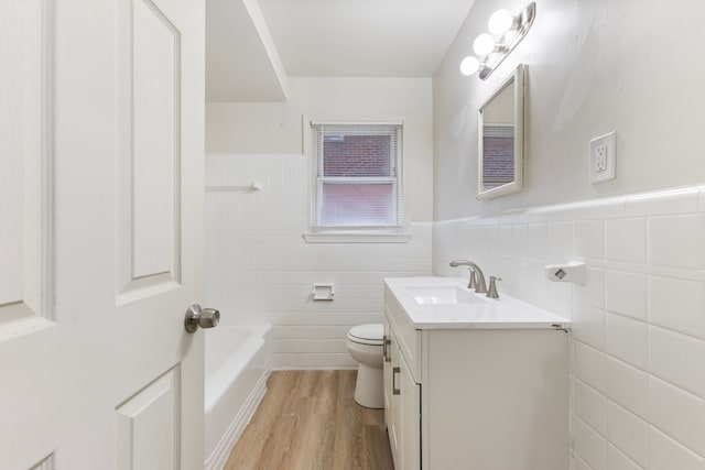 full bath featuring wainscoting, toilet, a tub, wood finished floors, and vanity