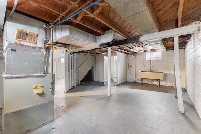 basement featuring a sink, visible vents, and heating unit