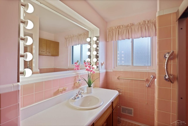 bathroom with wainscoting, visible vents, tile walls, and vanity