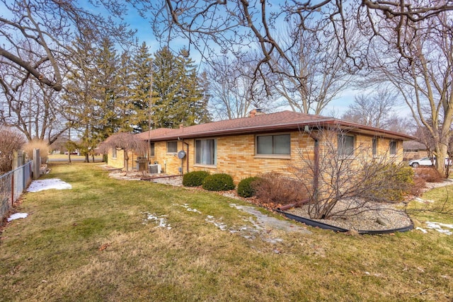 exterior space with a yard, brick siding, a chimney, and fence