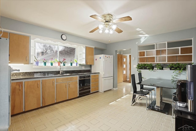 kitchen featuring brown cabinets, dark countertops, freestanding refrigerator, a sink, and dishwasher