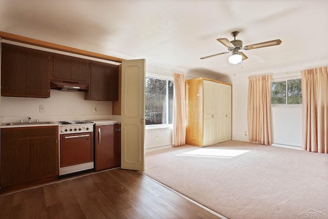 kitchen featuring under cabinet range hood, a sink, electric stove, light countertops, and dark carpet