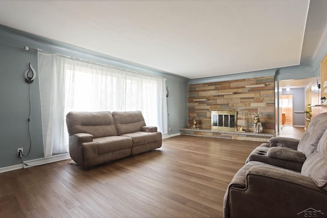 living area with baseboards, wood finished floors, and a stone fireplace