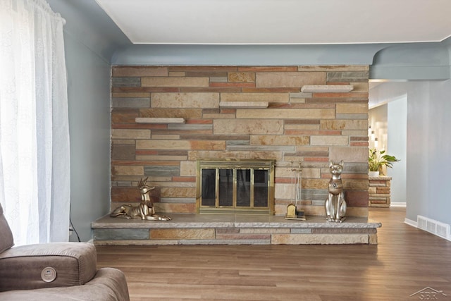 room details with baseboards, a fireplace, visible vents, and wood finished floors