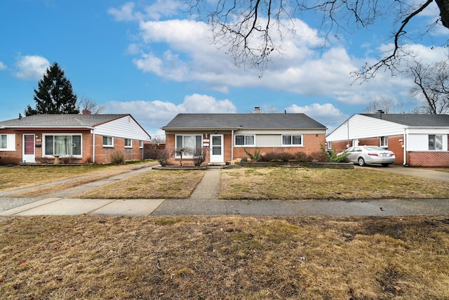 view of front facade with brick siding, driveway, and a front lawn