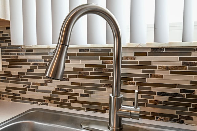 interior details featuring backsplash and a sink