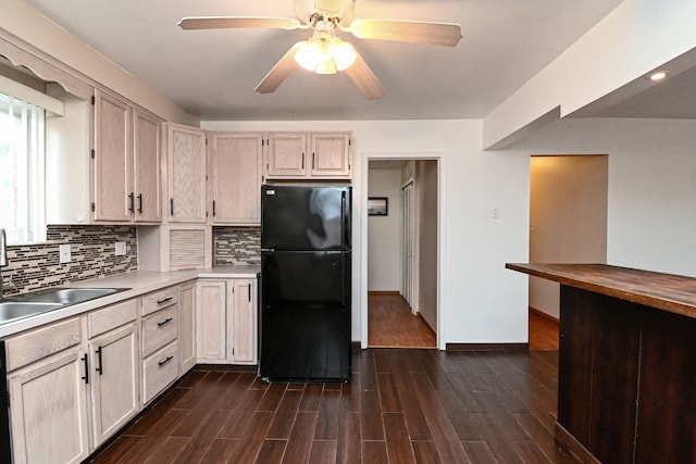 kitchen featuring wood tiled floor, backsplash, freestanding refrigerator, and a sink