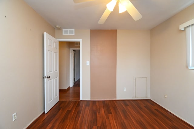 empty room featuring ceiling fan, visible vents, and wood finished floors