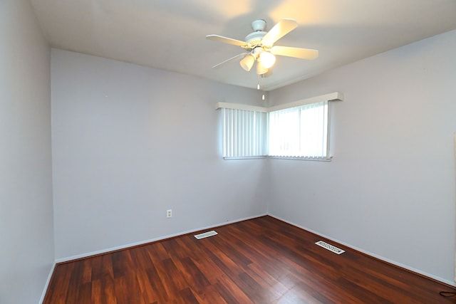 spare room featuring visible vents, baseboards, dark wood-type flooring, and a ceiling fan