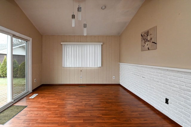 empty room with visible vents, a healthy amount of sunlight, lofted ceiling, and wood finished floors