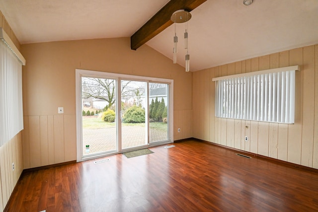 unfurnished room featuring lofted ceiling with beams, wood finished floors, and visible vents