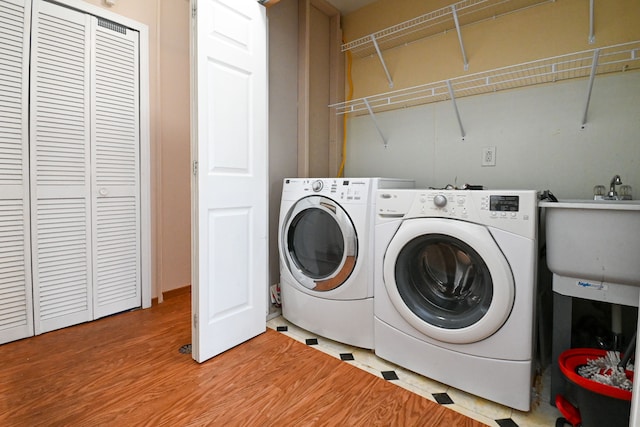 laundry area with laundry area, separate washer and dryer, light wood-style flooring, and a sink