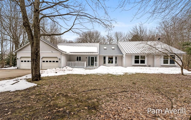 ranch-style home with an attached garage, a standing seam roof, and metal roof