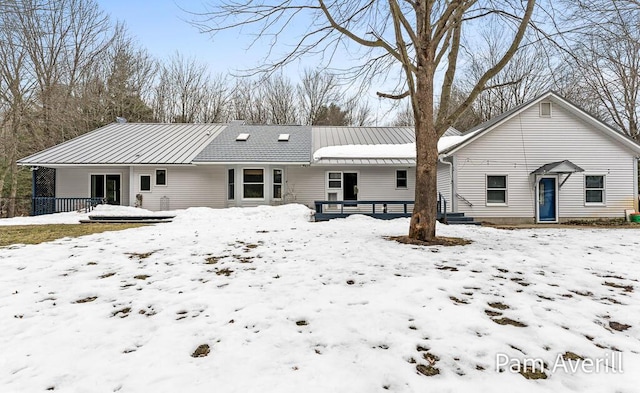 snow covered back of property with metal roof and a standing seam roof