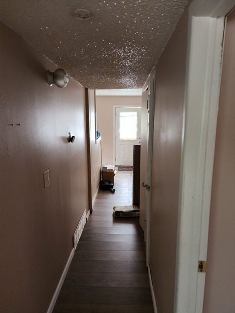 corridor featuring visible vents, baseboards, and hardwood / wood-style floors