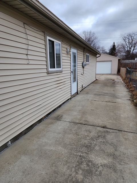 view of side of home featuring a detached garage, fence, and an outdoor structure