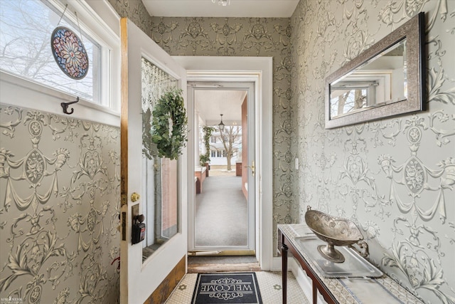 doorway featuring a healthy amount of sunlight and wallpapered walls