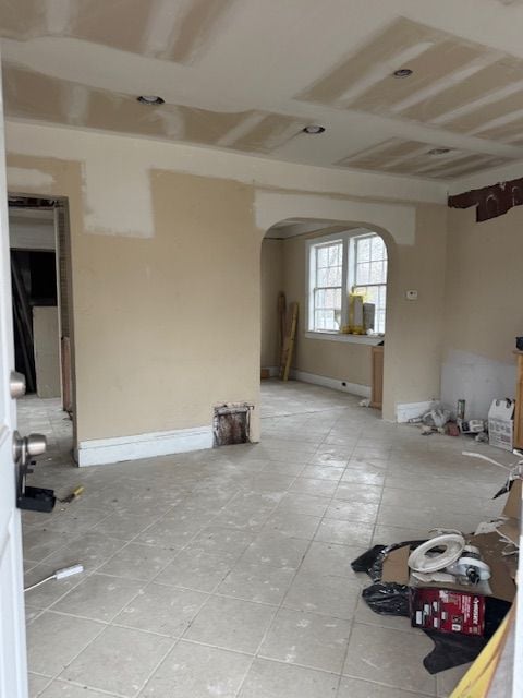 empty room featuring arched walkways and baseboards