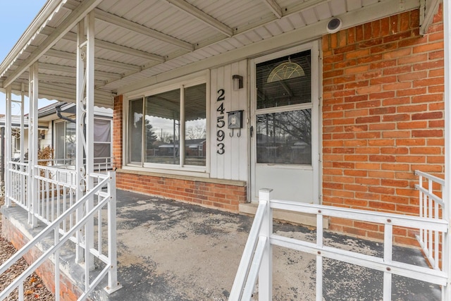 doorway to property with covered porch and brick siding