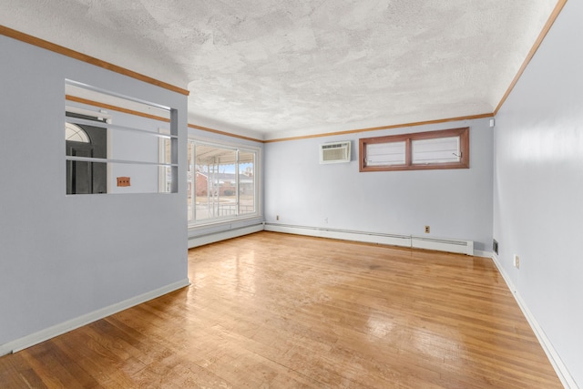 empty room with a baseboard radiator, a textured ceiling, a wall mounted air conditioner, baseboards, and hardwood / wood-style flooring