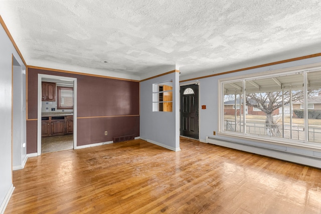 unfurnished living room featuring a baseboard heating unit, visible vents, baseboards, and wood finished floors