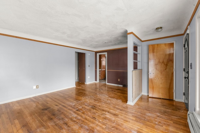 unfurnished room featuring a baseboard heating unit, crown molding, a textured ceiling, and light wood-style floors