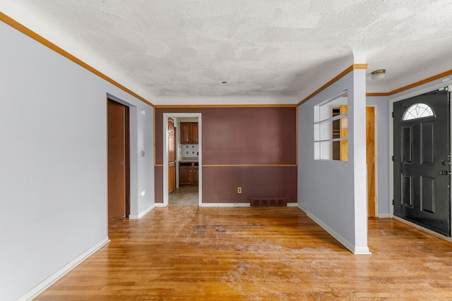 entryway with a textured ceiling, wood finished floors, visible vents, and baseboards