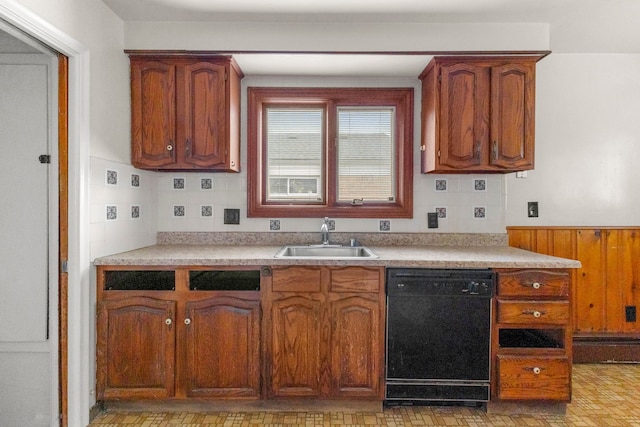 kitchen with brown cabinets, black dishwasher, light countertops, and a sink