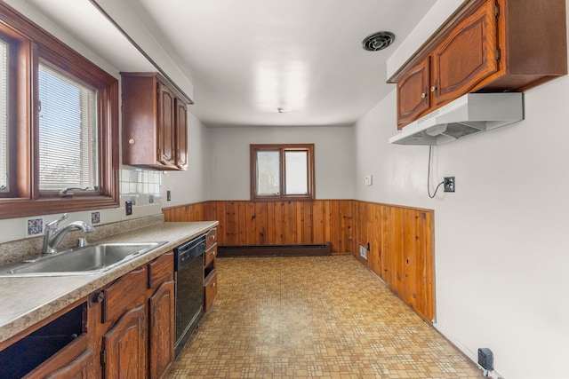 kitchen with wooden walls, dishwasher, a wainscoted wall, a baseboard heating unit, and a sink