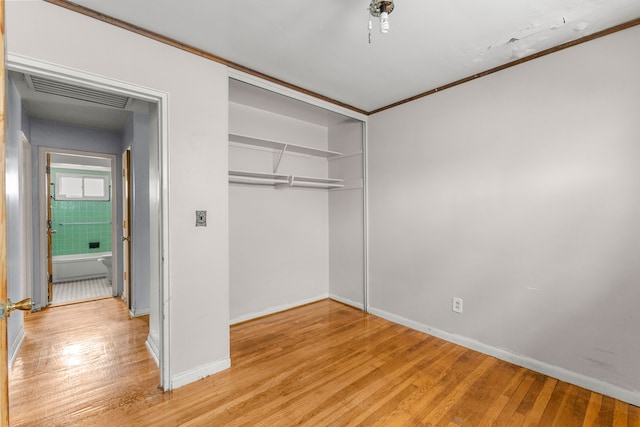 unfurnished bedroom with visible vents, baseboards, ornamental molding, a closet, and light wood-type flooring