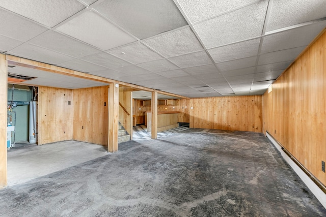 finished below grade area with stairway, a paneled ceiling, and wooden walls