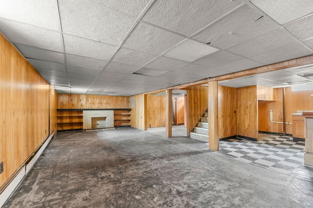 finished basement with a baseboard radiator, wooden walls, stairway, and a fireplace