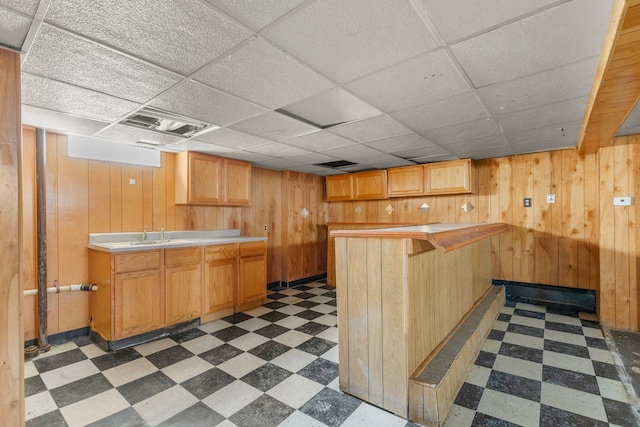 kitchen with a peninsula, wood walls, visible vents, light countertops, and tile patterned floors