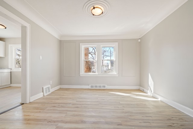 spare room with light wood-style flooring, visible vents, and baseboards