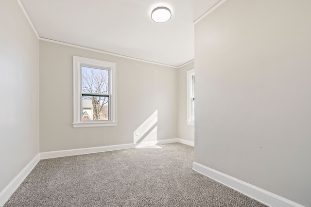 empty room with carpet floors, crown molding, and baseboards