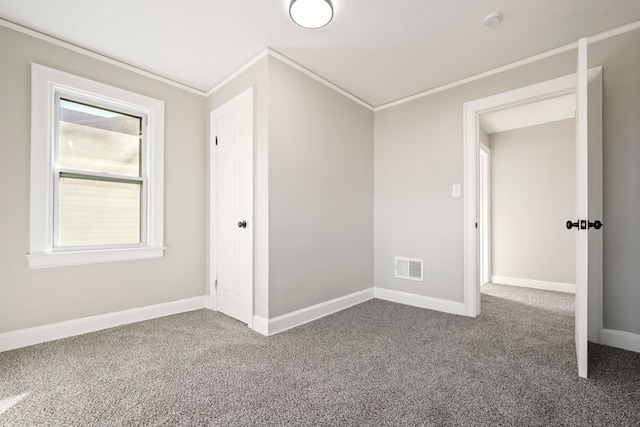 unfurnished bedroom featuring dark carpet, visible vents, crown molding, and baseboards