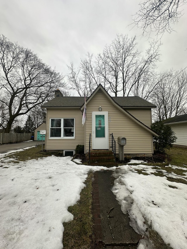 bungalow featuring entry steps, fence, and a chimney