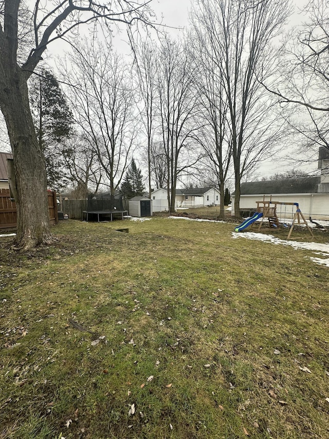 view of yard with an outbuilding, a playground, a storage shed, fence, and a trampoline