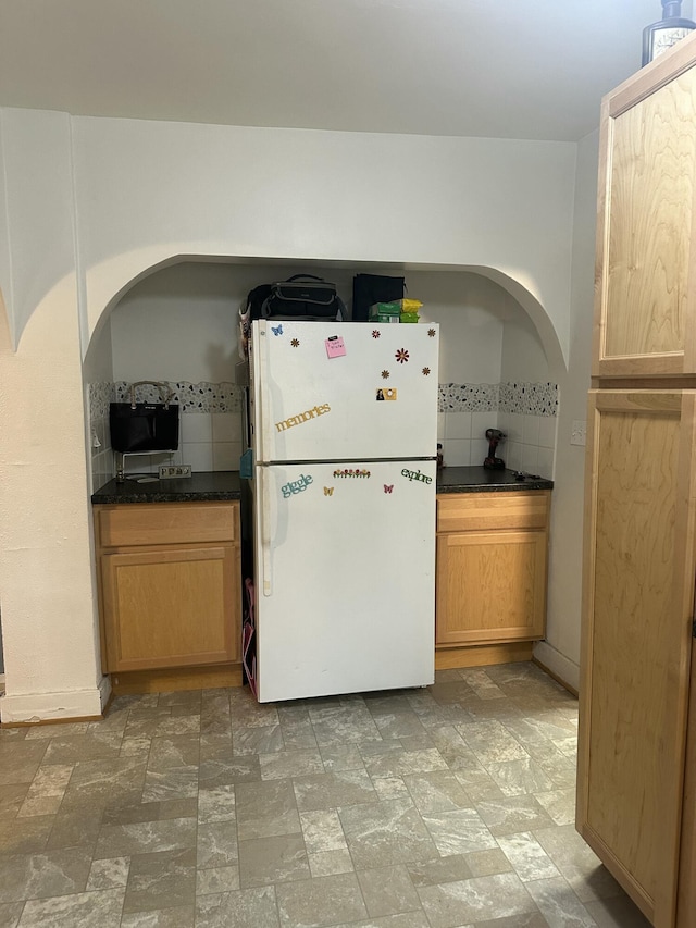 kitchen featuring stone finish floor, dark countertops, and freestanding refrigerator