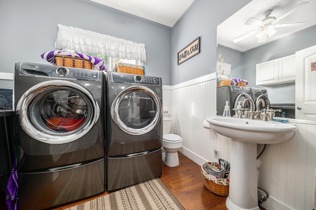 washroom with wainscoting, ceiling fan, separate washer and dryer, wood finished floors, and laundry area