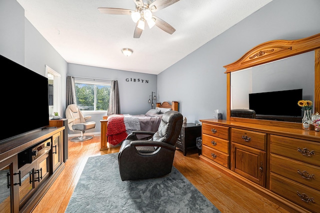 bedroom with ceiling fan, light wood-style flooring, and vaulted ceiling