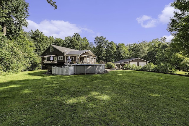 view of yard featuring a detached garage, an outdoor pool, and a wooden deck