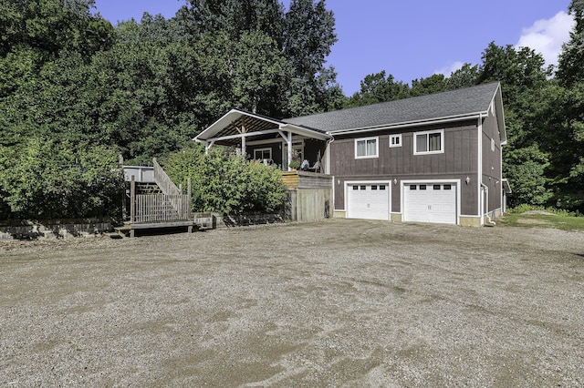 view of front of home with an attached garage, stairs, and dirt driveway